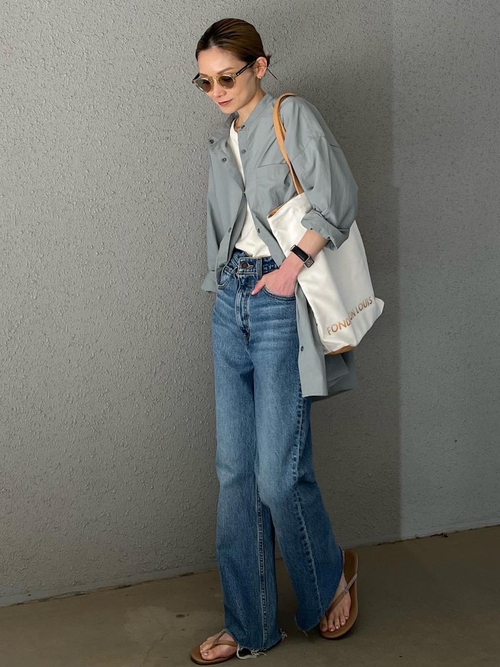 ブルー系のデニムパンツ、ベージュ系のビーチサンダル、ブルー系のラッシュガードを着用したレディースの春コーディネートの2枚目の写真