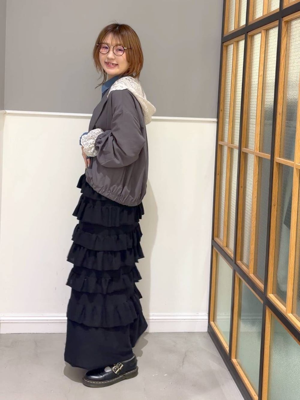 ブルー系のシャツ/ブラウス、ブラック系のスカート、グレー系のブルゾンを着用したレディースの春コーディネートの2枚目の写真