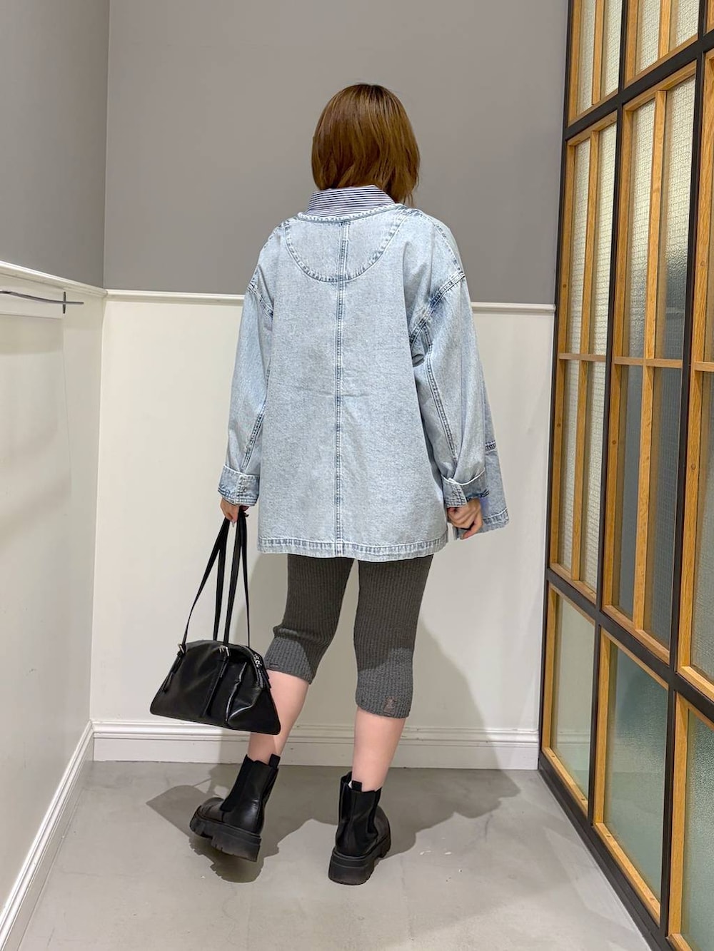 ブラック系のボストンバッグ、ブラック系のブーツ、ブルー系のシャツ/ブラウスを着用したレディースの冬コーディネートの3枚目の写真