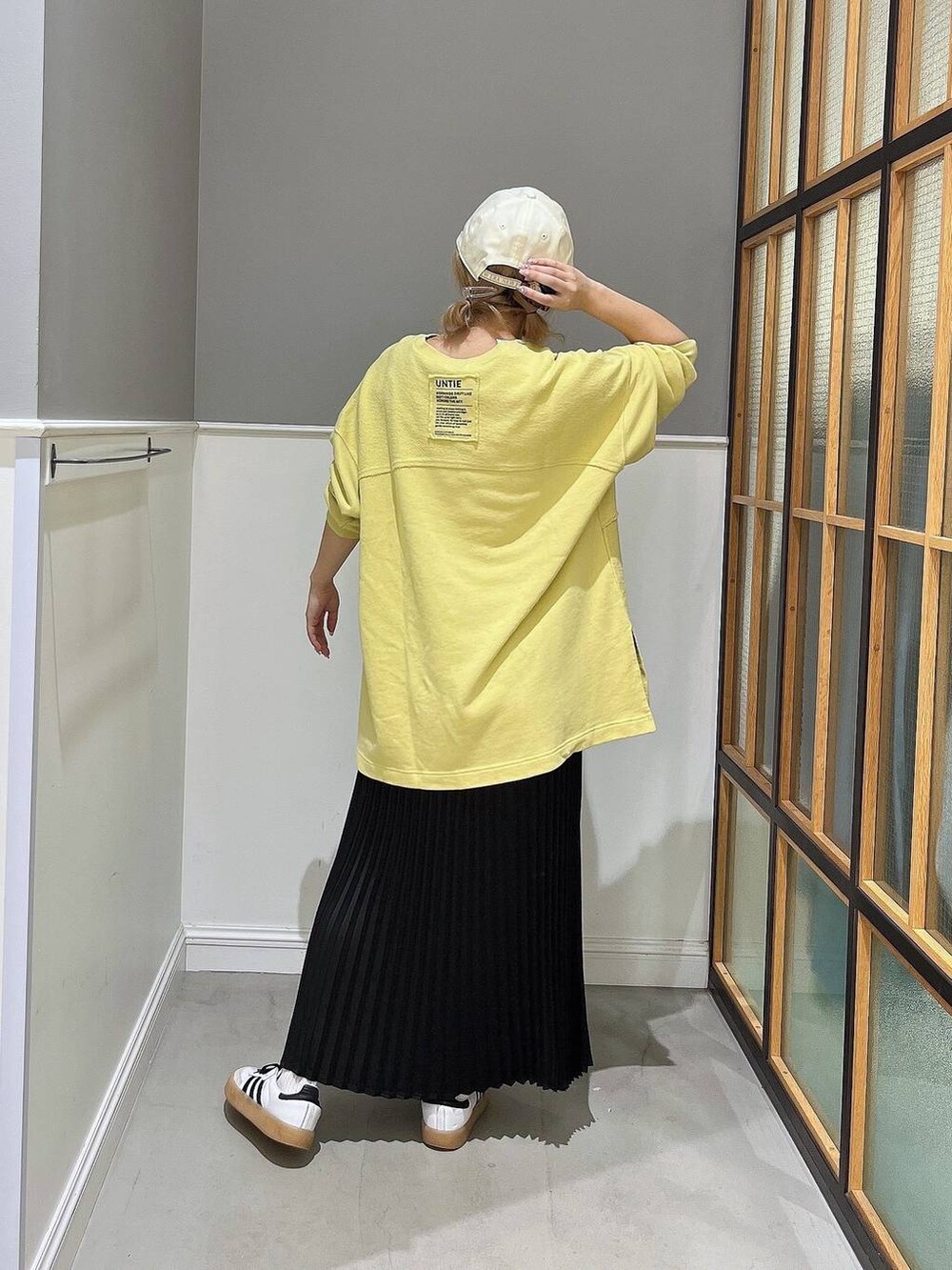 ブラック系のスカート、イエロー系のTシャツ/カットソー、ホワイト系のキャップを着用したレディースの秋コーディネートの3枚目の写真