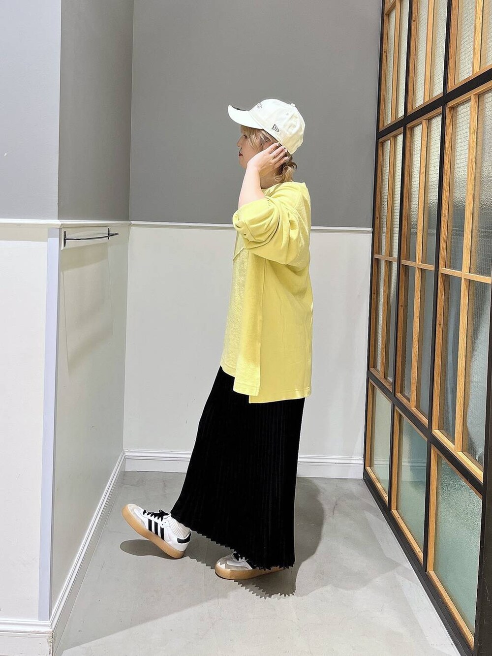 ブラック系のスカート、イエロー系のTシャツ/カットソー、ホワイト系のキャップを着用したレディースの秋コーディネートの2枚目の写真