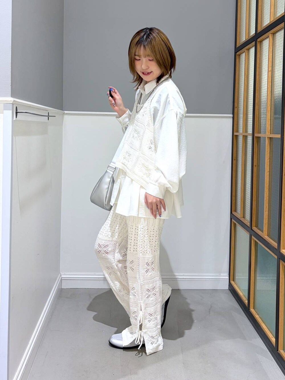 シルバー系のショルダーバッグ、ホワイト系のシャツ/ブラウス、シルバー系のパンプスを着用したレディースの冬コーディネートの2枚目の写真