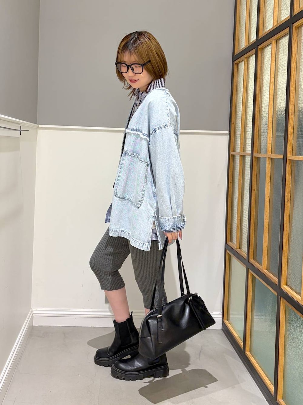 ブラック系のボストンバッグ、ブラック系のブーツ、ブルー系のシャツ/ブラウスを着用したレディースの冬コーディネートの2枚目の写真