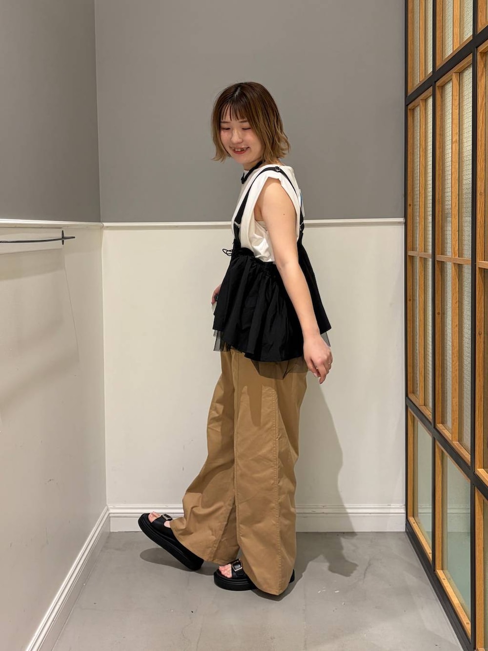 ベージュ系のその他パンツ、ブラック系のベスト、ブラック系のサンダルを着用したレディースの夏コーディネートの2枚目の写真