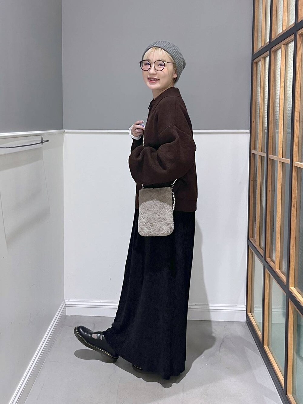 ブラウン系のショルダーバッグ、ブラウン系のブルゾン、ブラック系のスカートを着用したレディースの秋コーディネートの2枚目の写真