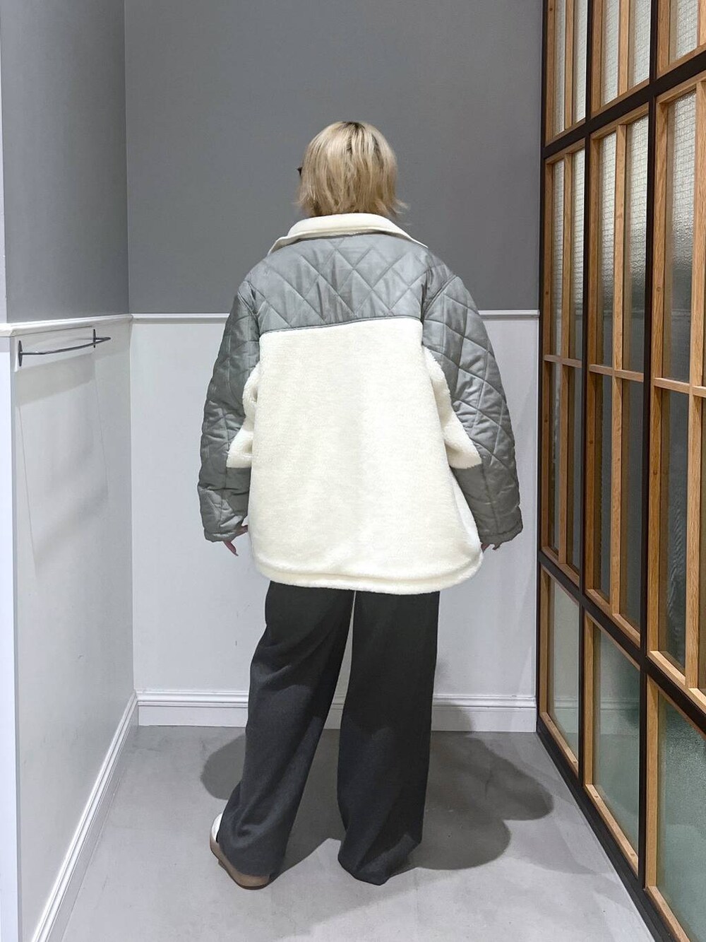 グリーン系のブルゾン、イエロー系のニット/セーター、グレー系のその他パンツを着用したレディースの冬コーディネートの4枚目の写真