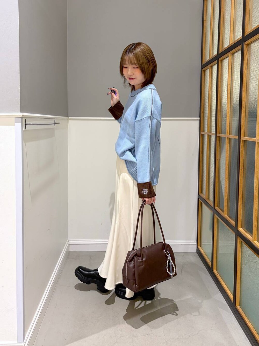 ブラック系のブーツ、ホワイト系のスカート、ブルー系のニット/セーターを着用したレディースの冬コーディネートの2枚目の写真