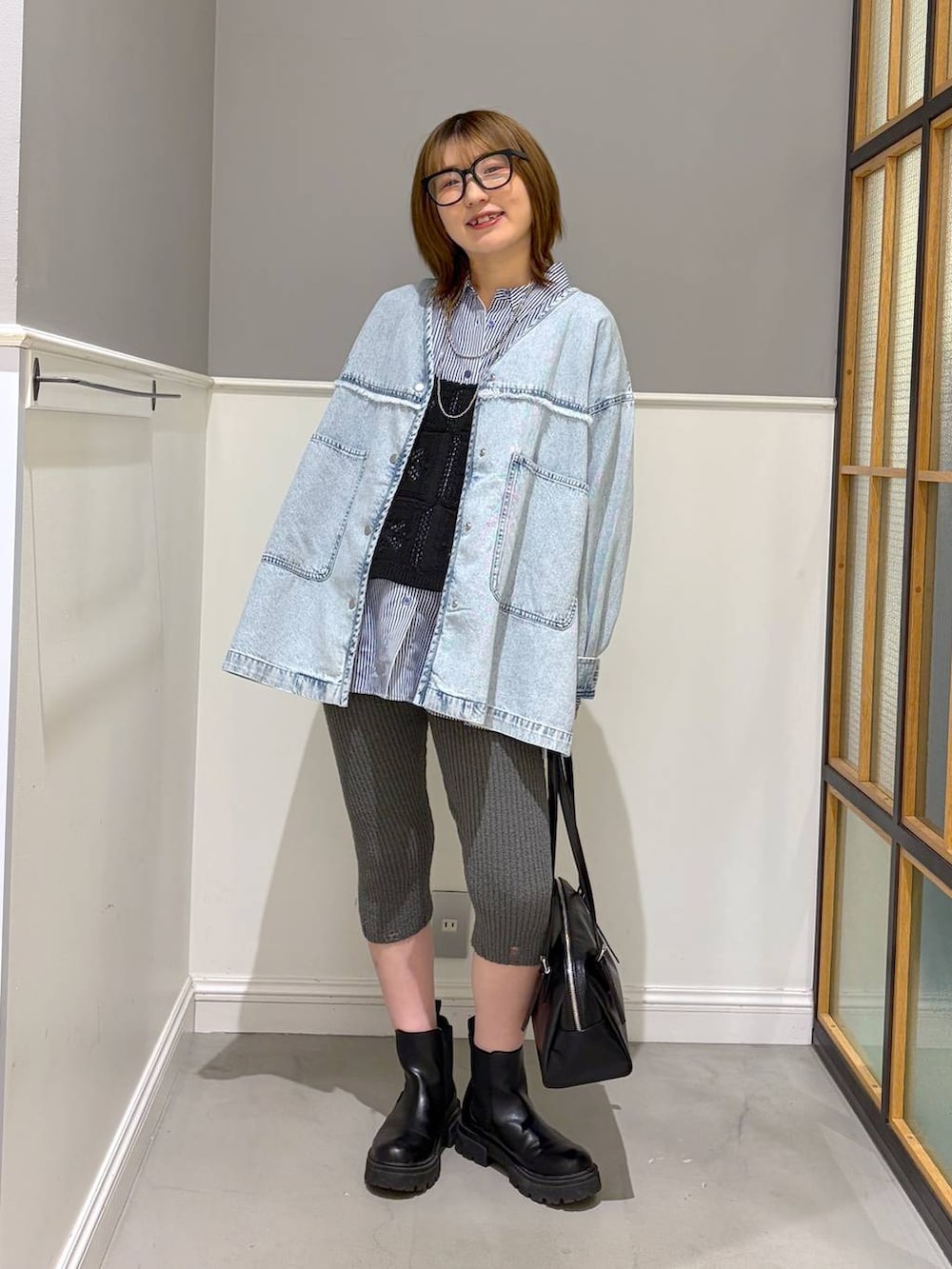 ブラック系のボストンバッグ、ブラック系のブーツ、ブルー系のシャツ/ブラウスを着用したレディースの冬コーディネートの4枚目の写真