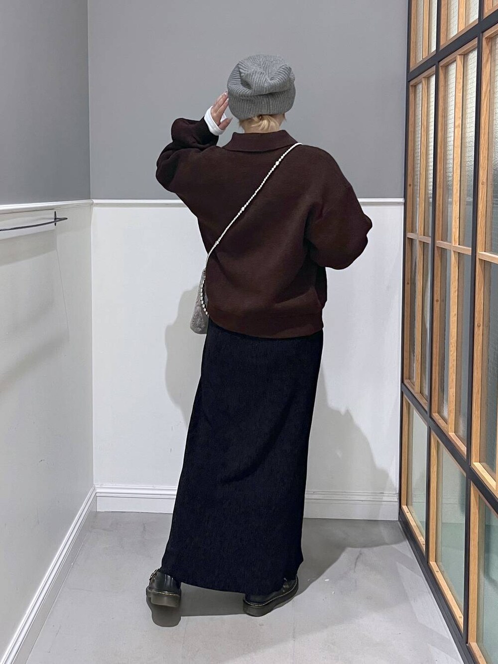 ブラウン系のショルダーバッグ、ブラウン系のブルゾン、ブラック系のスカートを着用したレディースの秋コーディネートの3枚目の写真