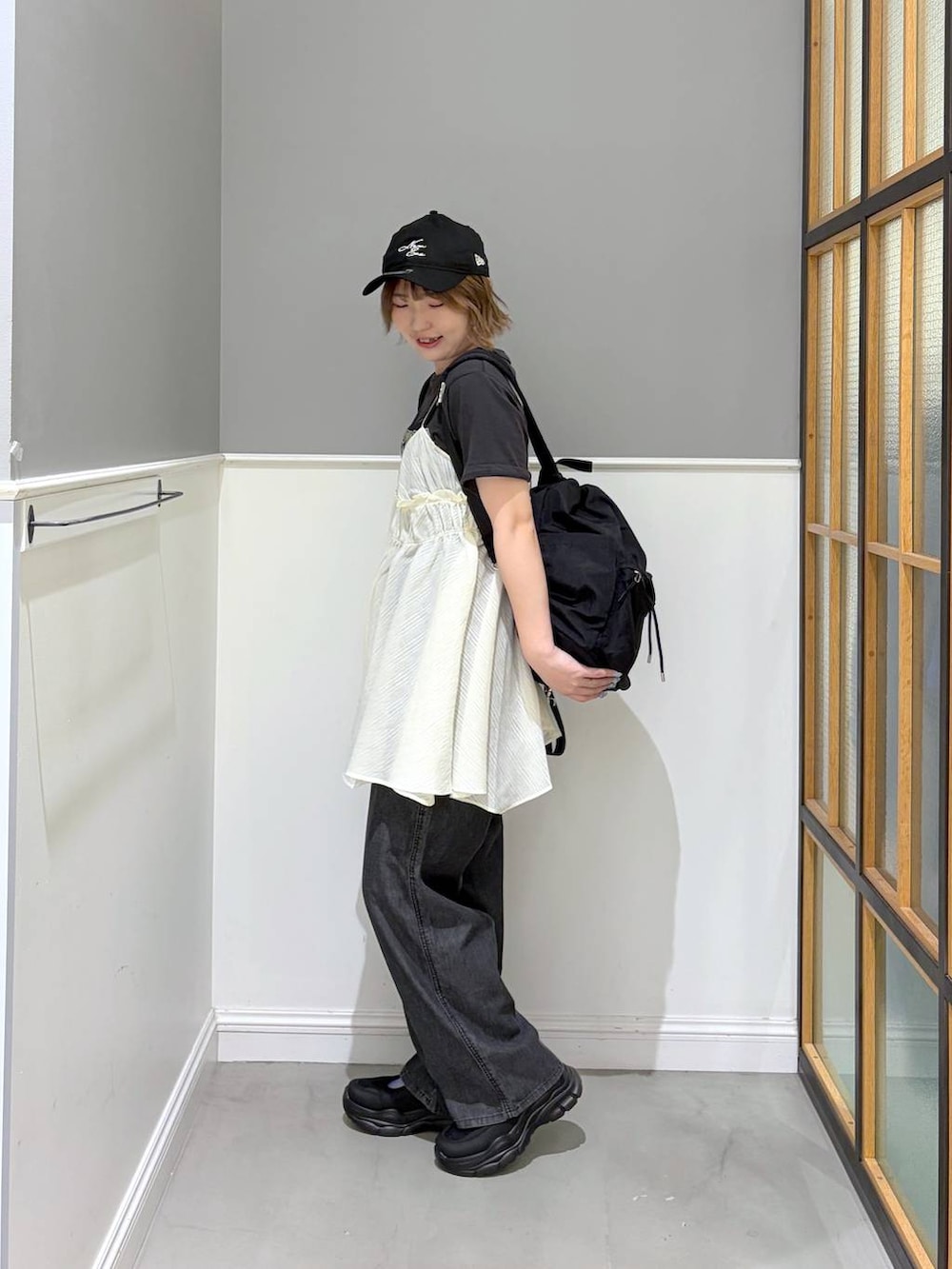 ブラック系のデニムパンツ、ブラック系のバックパック/リュック、ブラック系のスニーカーを着用したレディースの春コーディネートの2枚目の写真