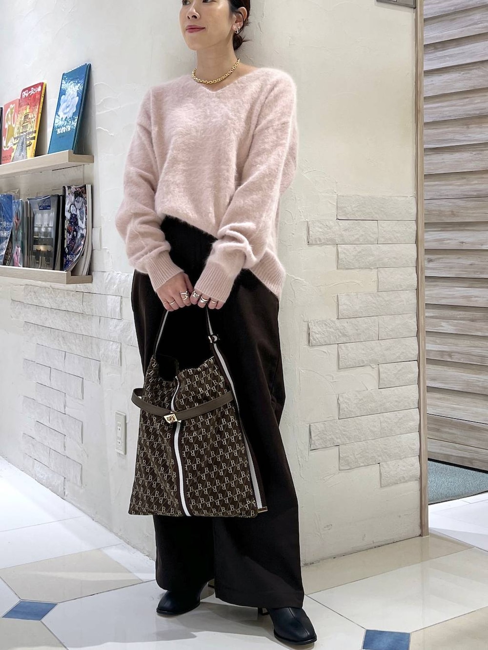 ピンク系のニット/セーター、ブラウン系のショルダーバッグ、ブラック系のブーツを着用したレディースの秋コーディネートの2枚目の写真