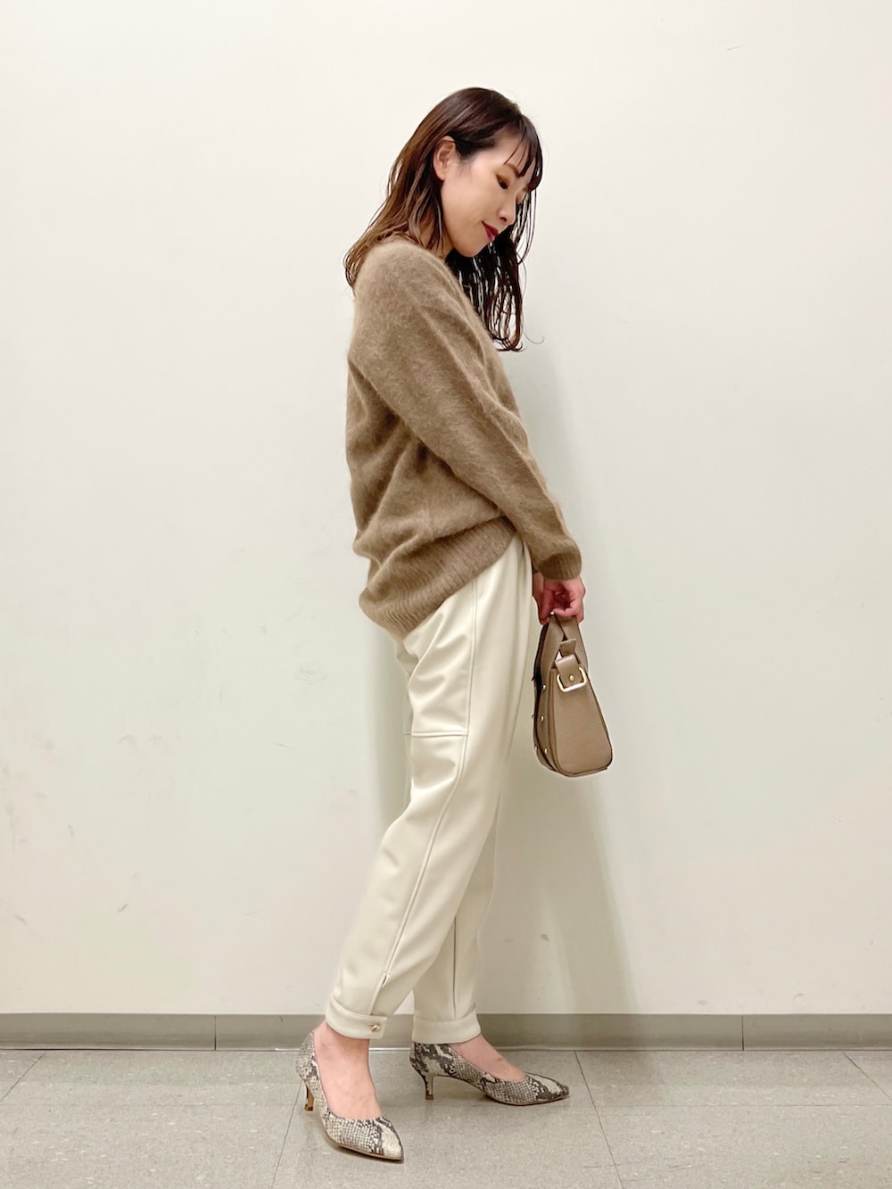 ブラウン系のニット/セーター、ホワイト系のその他パンツ、ベージュ系のショルダーバッグを着用したレディースの秋コーディネートの2枚目の写真