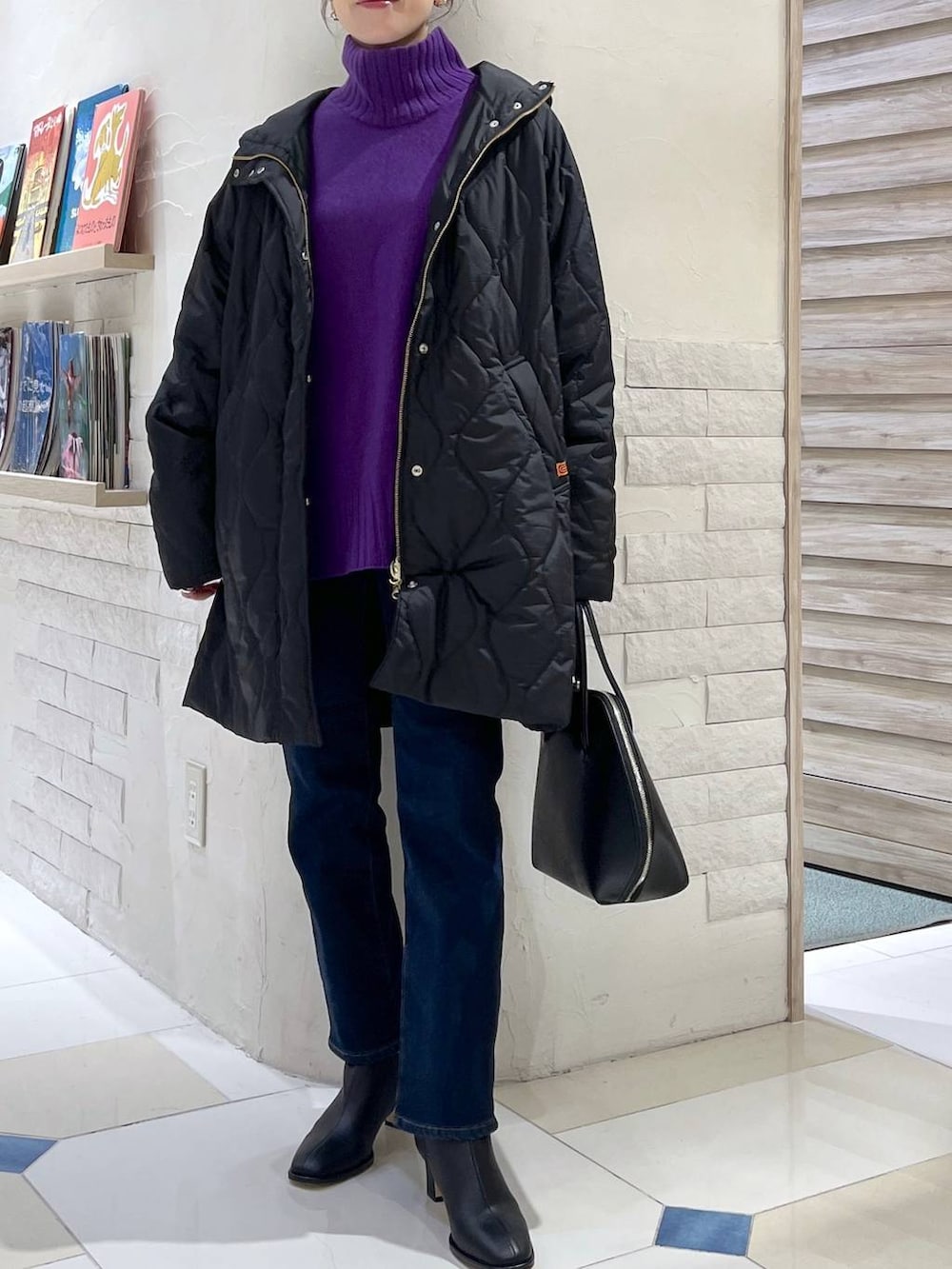 ブラック系のトートバッグ、ブルー系のデニムパンツ、パープル系のニット/セーターを着用したレディースの秋コーディネートの3枚目の写真