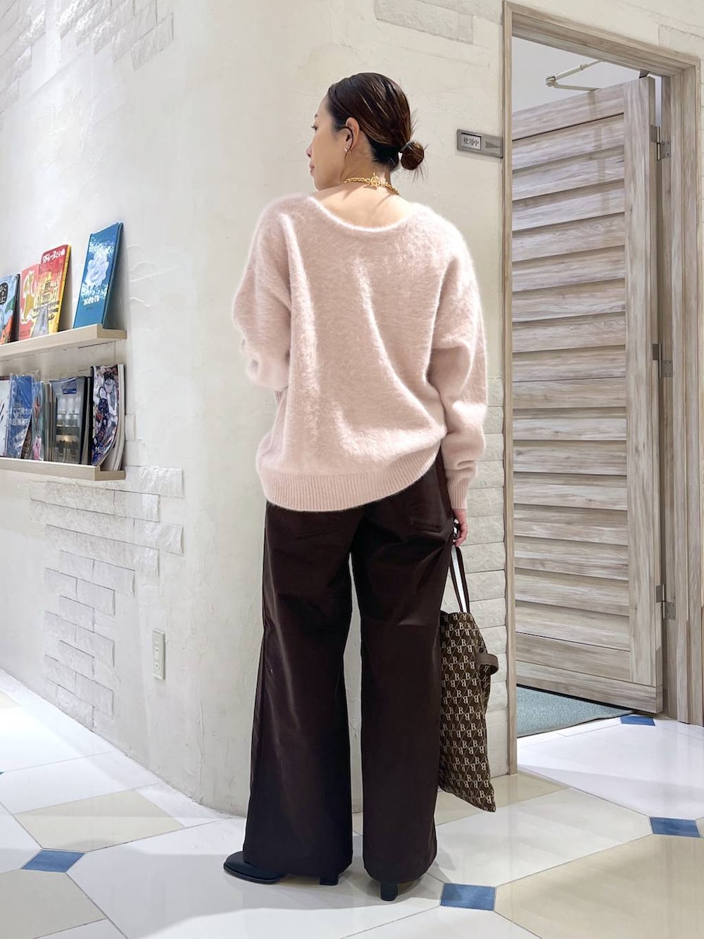 ピンク系のニット/セーター、ブラウン系のショルダーバッグ、ブラック系のブーツを着用したレディースの秋コーディネートの4枚目の写真