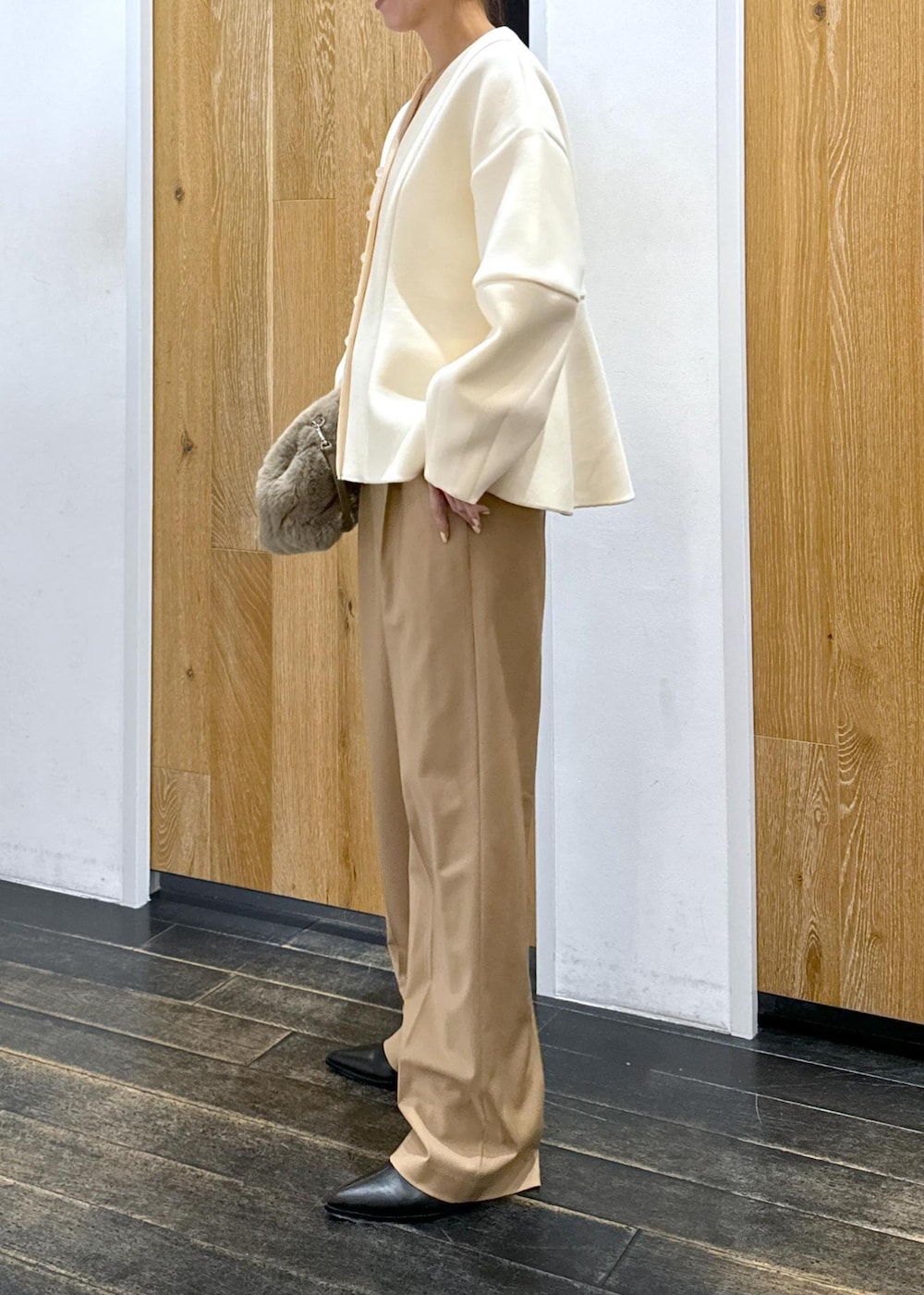 ブラック系のブーツ、ホワイト系のカーディガン/ボレロ、ベージュ系のスラックスを着用したレディースの秋コーディネートの3枚目の写真