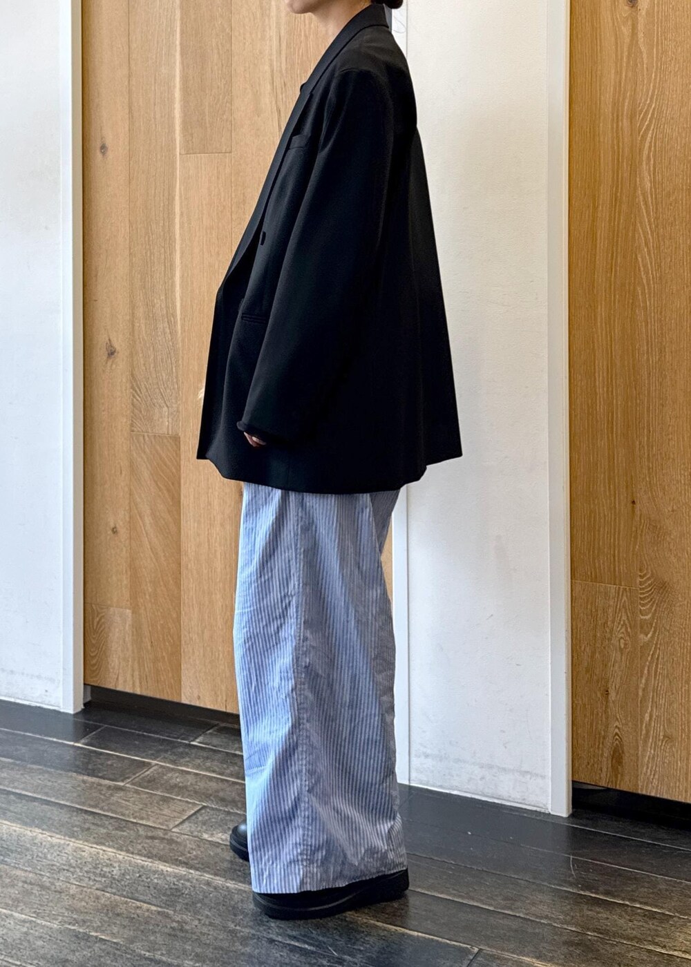 ブルー系のスラックス、ブラック系のテーラードジャケット、ベージュ系のトートバッグを着用したレディースの秋コーディネートの2枚目の写真