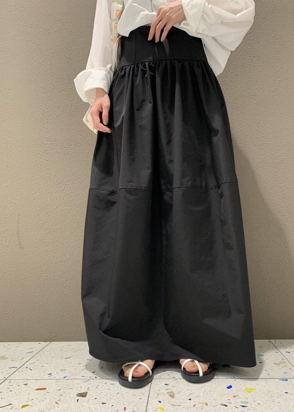 ブラック系のスカート、ホワイト系のサンダル、ホワイト系のシャツ/ブラウスを着用したレディースの春コーディネートの5枚目の写真