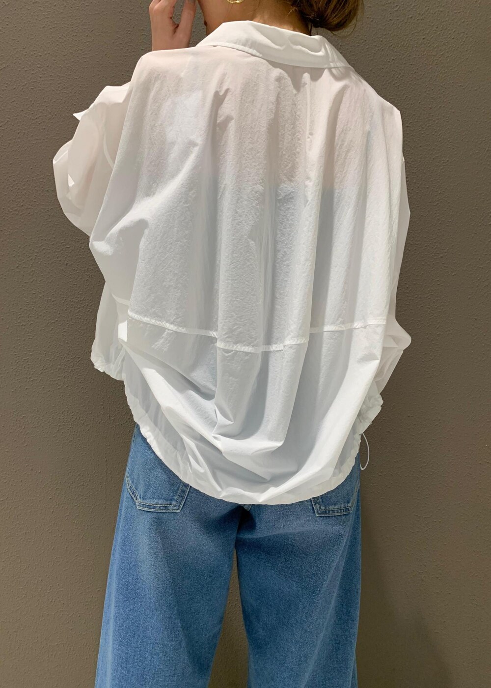 ブルー系のデニムパンツ、ブラック系のチューブトップ、ホワイト系のサンダルを着用したレディースの春コーディネートの5枚目の写真