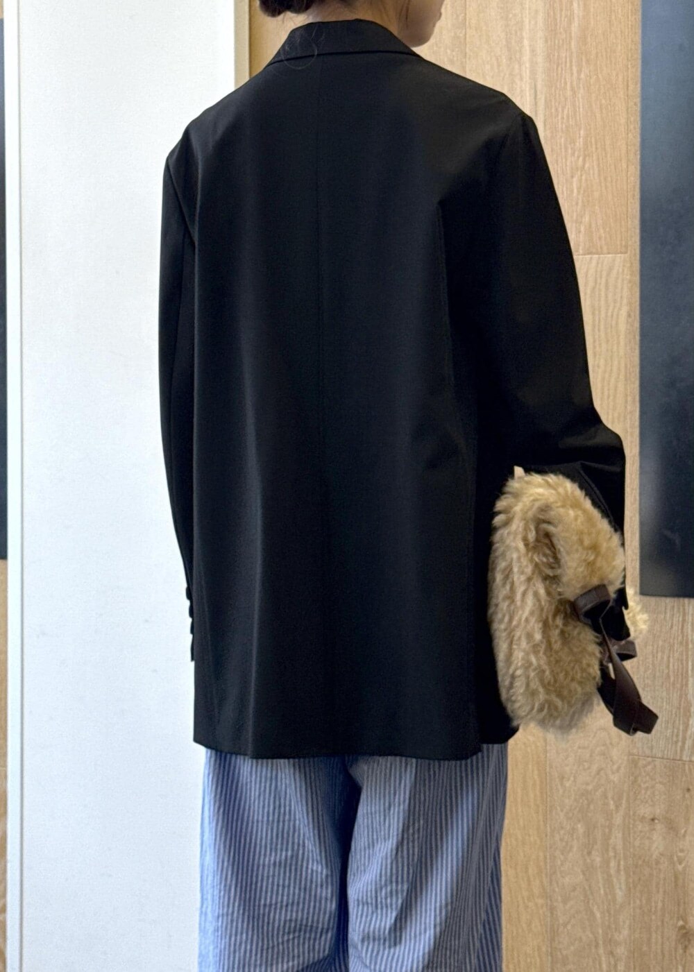 ブルー系のスラックス、ブラック系のテーラードジャケット、ベージュ系のトートバッグを着用したレディースの秋コーディネートの6枚目の写真