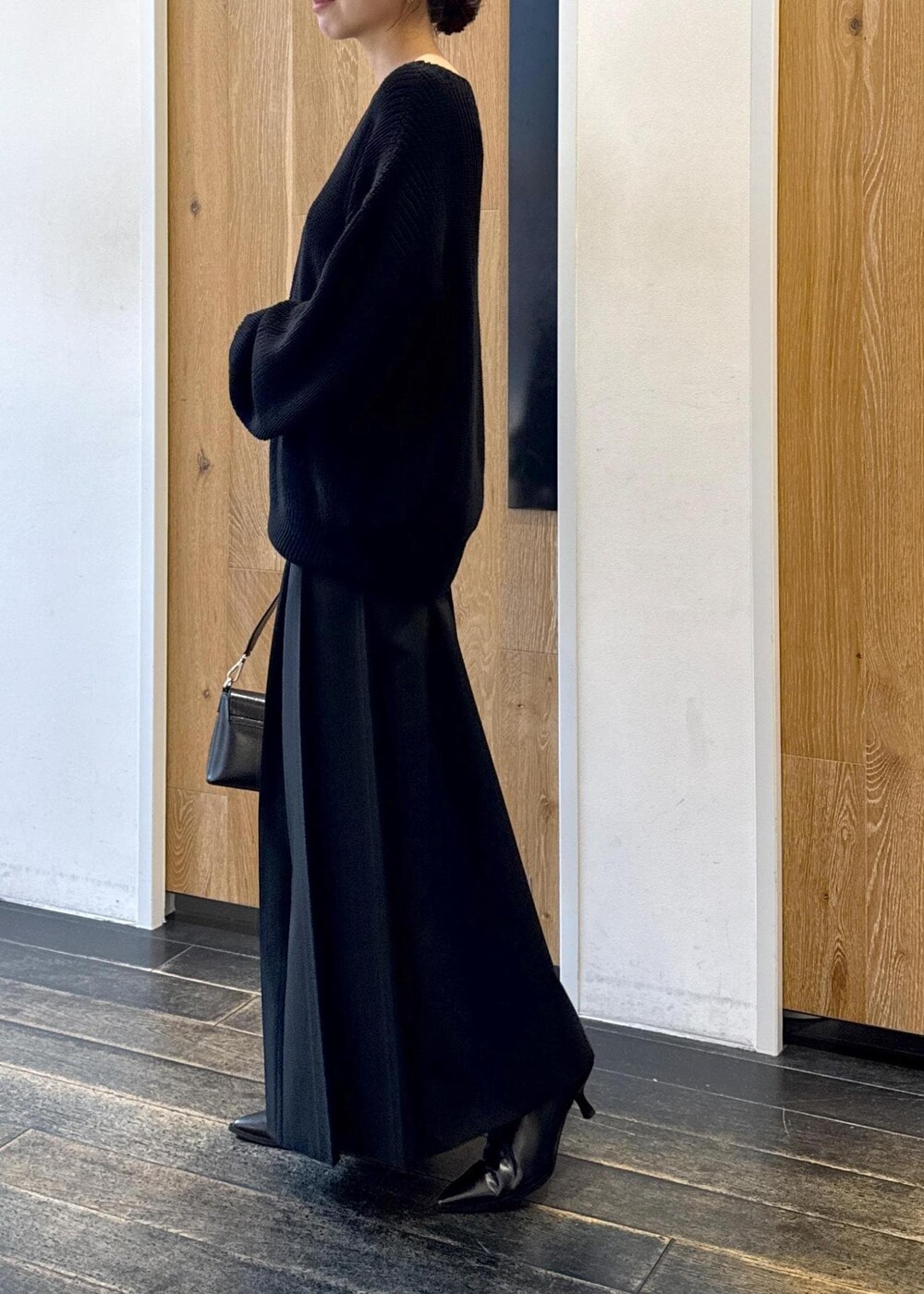 ブラック系のショルダーバッグ、ブラック系のスカート、ブラック系のブーツを着用したレディースの秋コーディネートの3枚目の写真