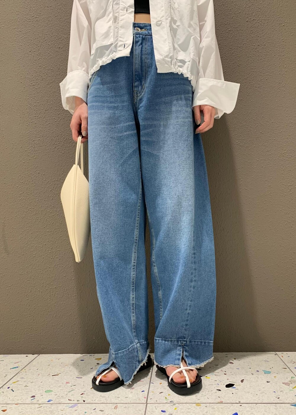 ブルー系のデニムパンツ、ブラック系のチューブトップ、ホワイト系のサンダルを着用したレディースの春コーディネートの6枚目の写真