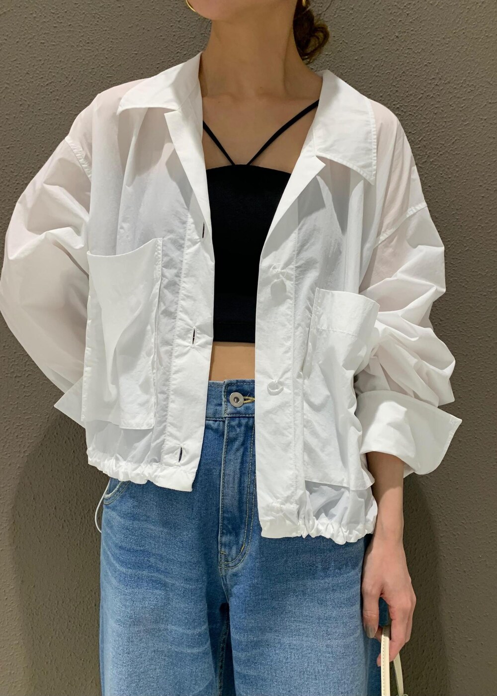 ブルー系のデニムパンツ、ブラック系のチューブトップ、ホワイト系のサンダルを着用したレディースの春コーディネートの4枚目の写真