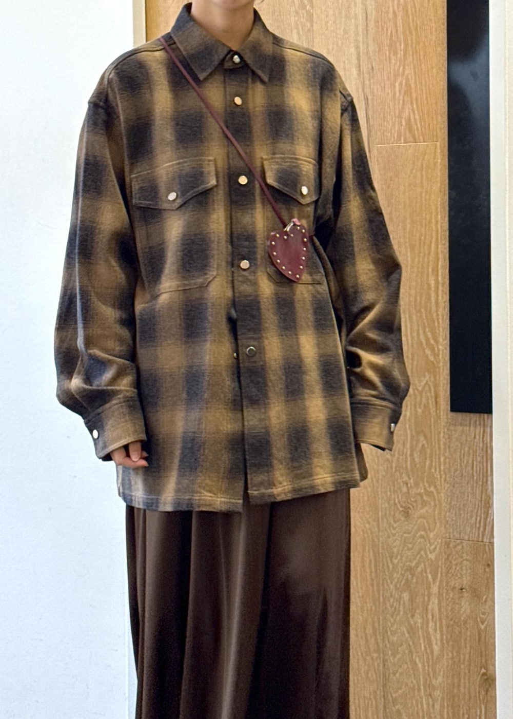 ブラック系のブーツ、ブラウン系のスカート、イエロー系のシャツ/ブラウスを着用したレディースの秋コーディネートの6枚目の写真