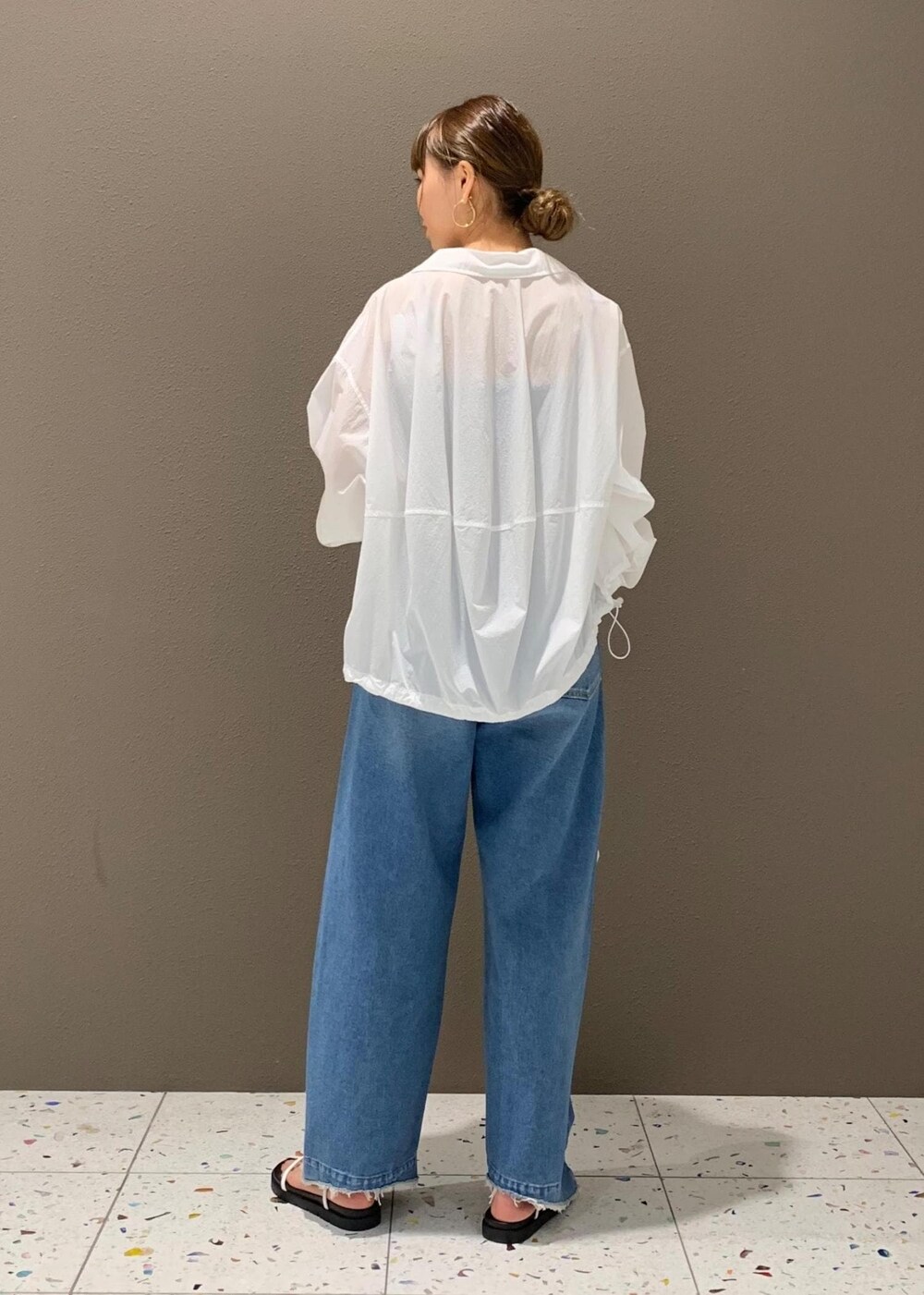 ブルー系のデニムパンツ、ブラック系のチューブトップ、ホワイト系のサンダルを着用したレディースの春コーディネートの3枚目の写真