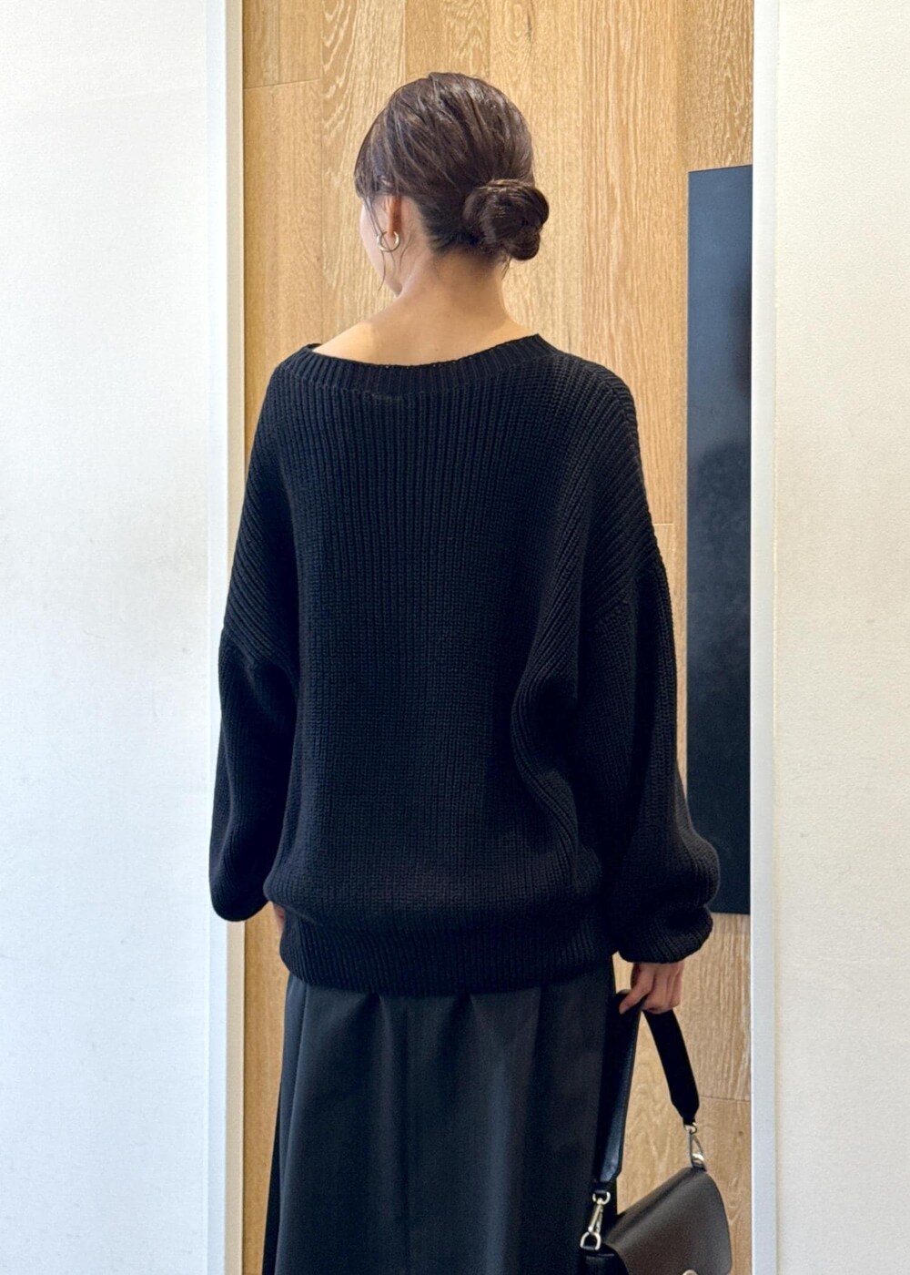 ブラック系のショルダーバッグ、ブラック系のスカート、ブラック系のブーツを着用したレディースの秋コーディネートの7枚目の写真