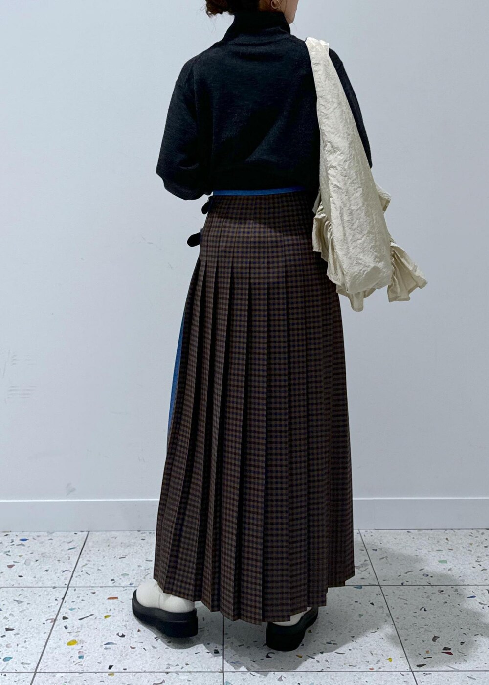 グレー系のスカート、ホワイト系のブーツ、グレー系のカーディガン/ボレロを着用したレディースの秋コーディネートの6枚目の写真