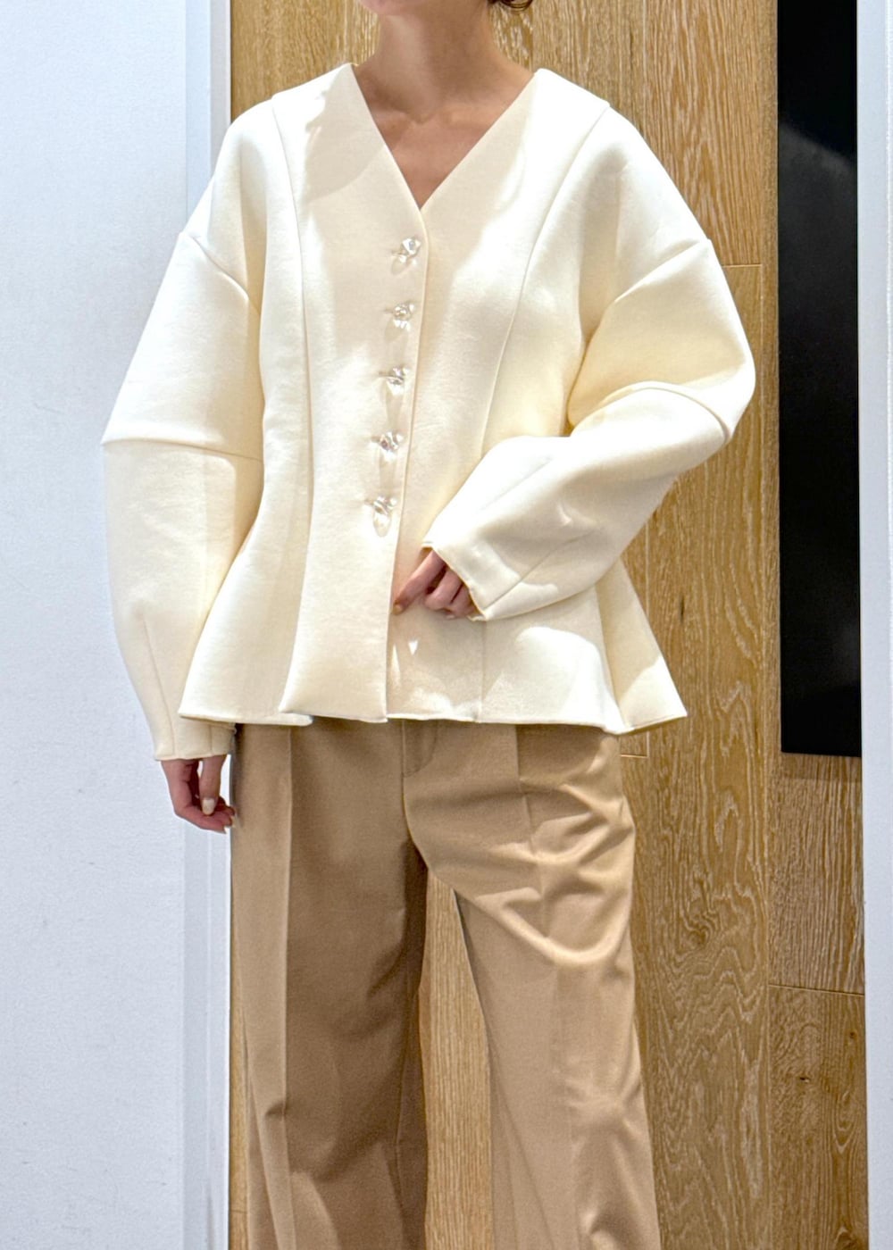 ブラック系のブーツ、ホワイト系のカーディガン/ボレロ、ベージュ系のスラックスを着用したレディースの秋コーディネートの5枚目の写真