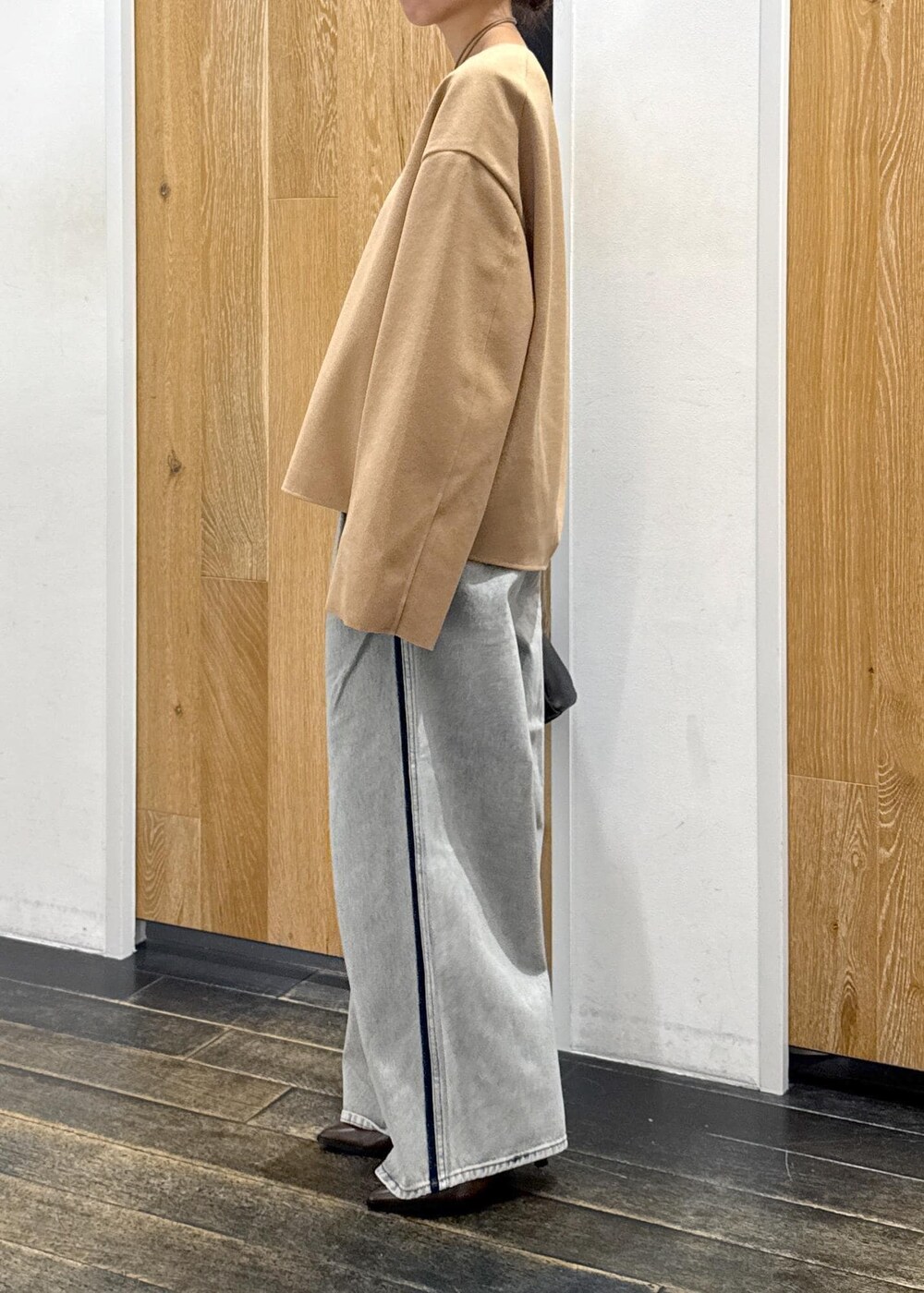 ブラウン系のブーツ、ベージュ系のTシャツ/カットソー、ブルー系のデニムパンツを着用したレディースの秋コーディネートの3枚目の写真