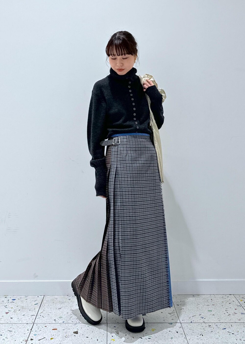 グレー系のスカート、ホワイト系のブーツ、グレー系のカーディガン/ボレロを着用したレディースの秋コーディネートの2枚目の写真