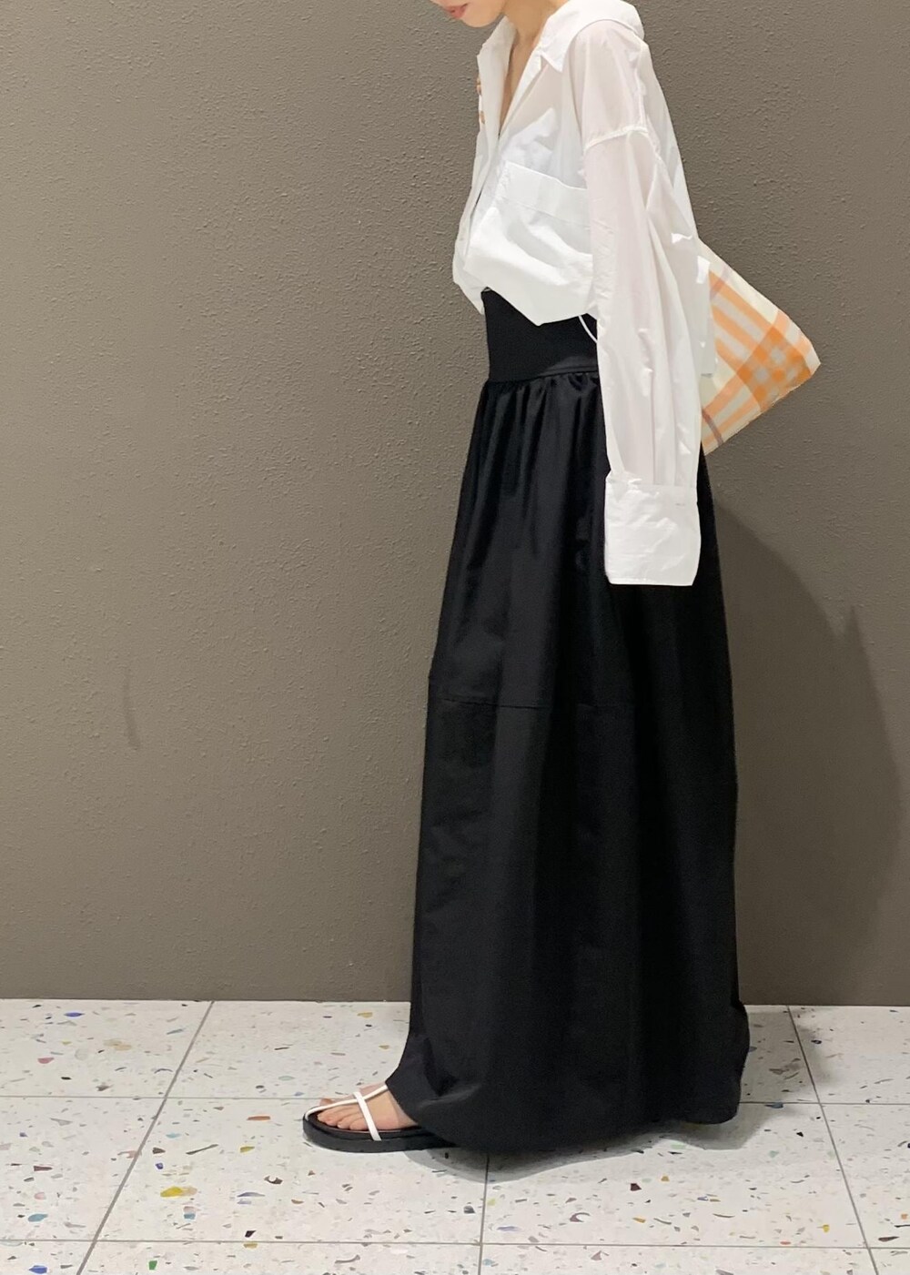 ブラック系のスカート、ホワイト系のサンダル、ホワイト系のシャツ/ブラウスを着用したレディースの春コーディネートの3枚目の写真