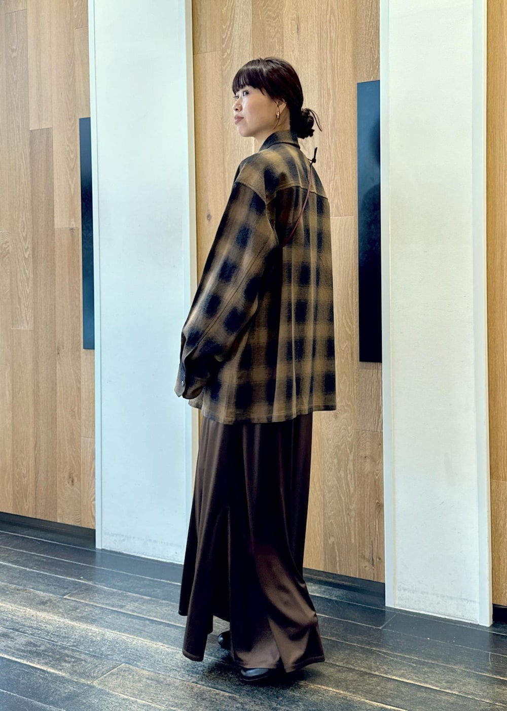 ブラック系のブーツ、ブラウン系のスカート、イエロー系のシャツ/ブラウスを着用したレディースの秋コーディネートの3枚目の写真