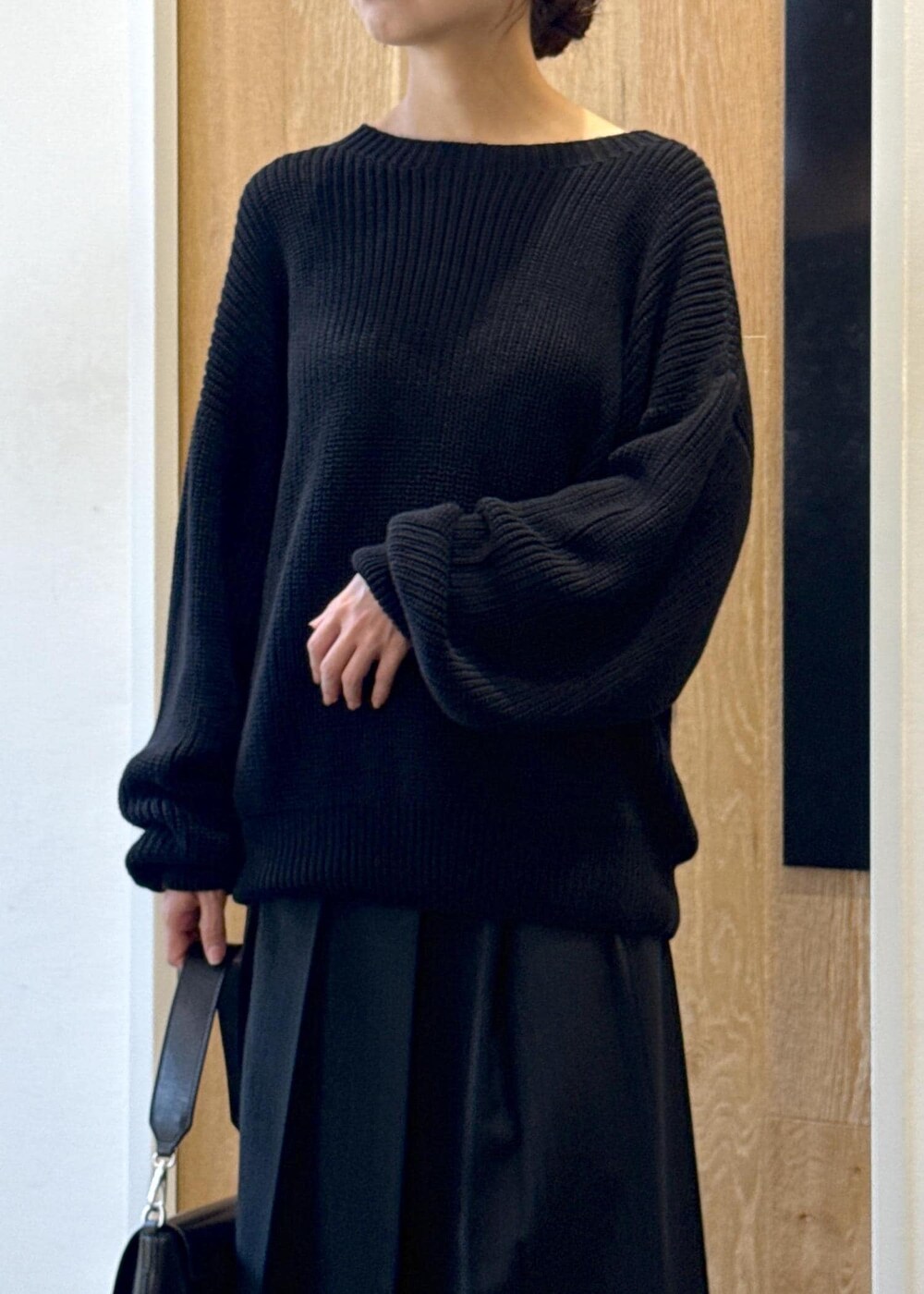 ブラック系のショルダーバッグ、ブラック系のスカート、ブラック系のブーツを着用したレディースの秋コーディネートの5枚目の写真