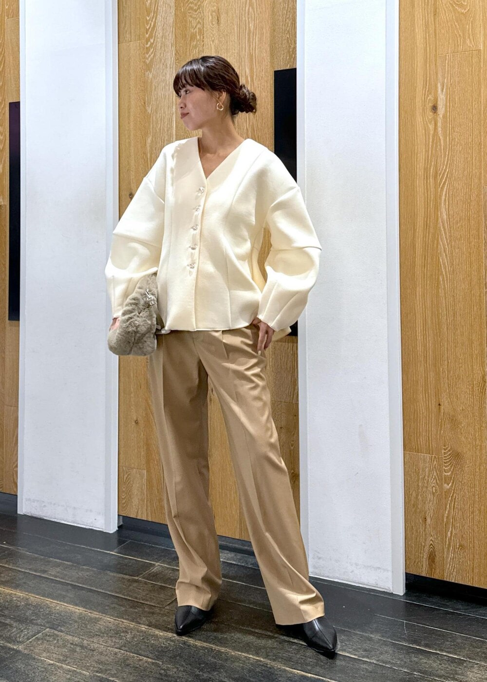 ブラック系のブーツ、ホワイト系のカーディガン/ボレロ、ベージュ系のスラックスを着用したレディースの秋コーディネートの2枚目の写真