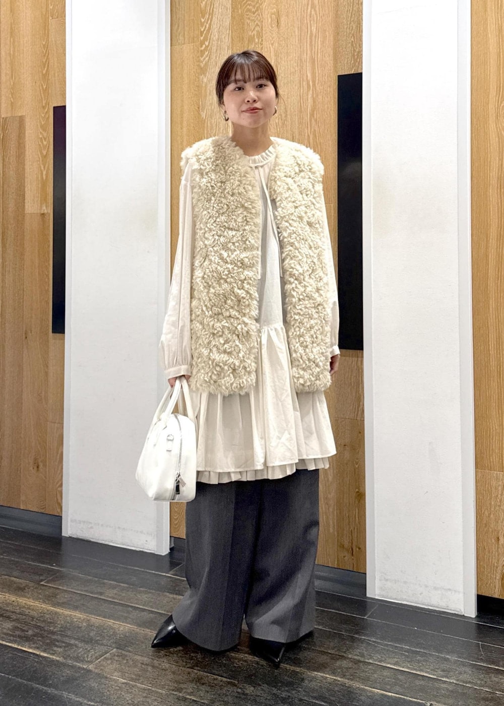 ベージュ系のその他アウター、ホワイト系のボストンバッグ、グレー系のスラックスを着用したレディースの冬コーディネートの2枚目の写真