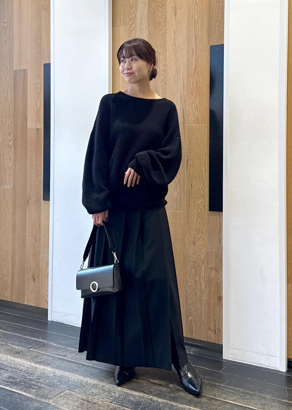 ブラック系のショルダーバッグ、ブラック系のスカート、ブラック系のブーツを着用したレディースの秋コーディネートの2枚目の写真