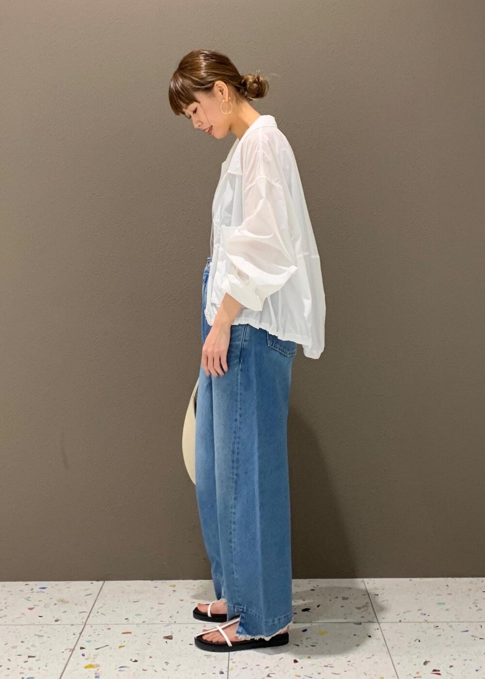 ブルー系のデニムパンツ、ブラック系のチューブトップ、ホワイト系のサンダルを着用したレディースの春コーディネートの2枚目の写真