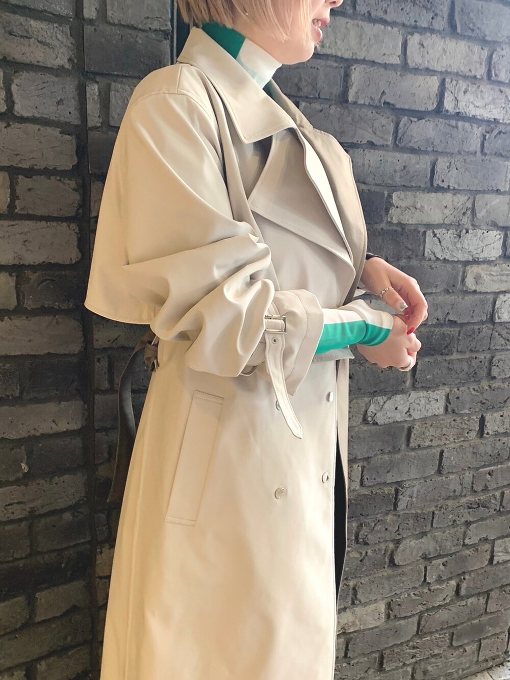 グリーン系のトップス、ブラック系のその他パンツ、ベージュ系のトレンチコートを着用したレディースの冬コーディネートの3枚目の写真