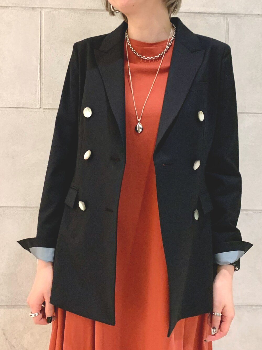 ブルー系のテーラードジャケット、オレンジ系のワンピース/ドレス、シルバー系のネックレスを着用したレディースの春コーディネートの2枚目の写真