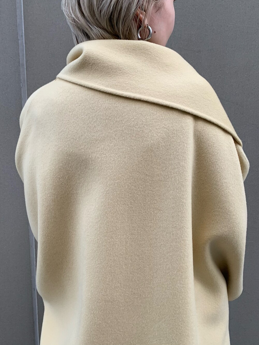 イエロー系のその他アウター、ブラウン系のスカート、ブラック系のブーツを着用したレディースの秋コーディネートの2枚目の写真