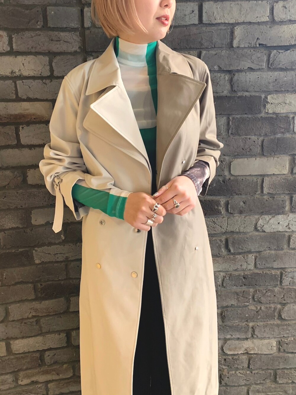 グリーン系のトップス、ブラック系のその他パンツ、ベージュ系のトレンチコートを着用したレディースの冬コーディネートの2枚目の写真