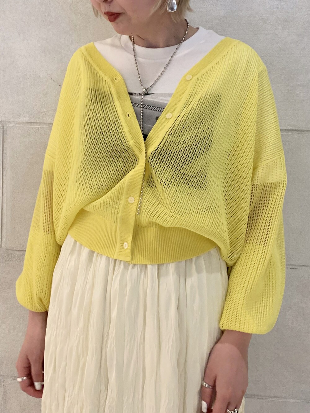 イエロー系のカーディガン/ボレロ、ホワイト系のTシャツ/カットソー、イエロー系のスカートを着用したレディースの春コーディネートの2枚目の写真
