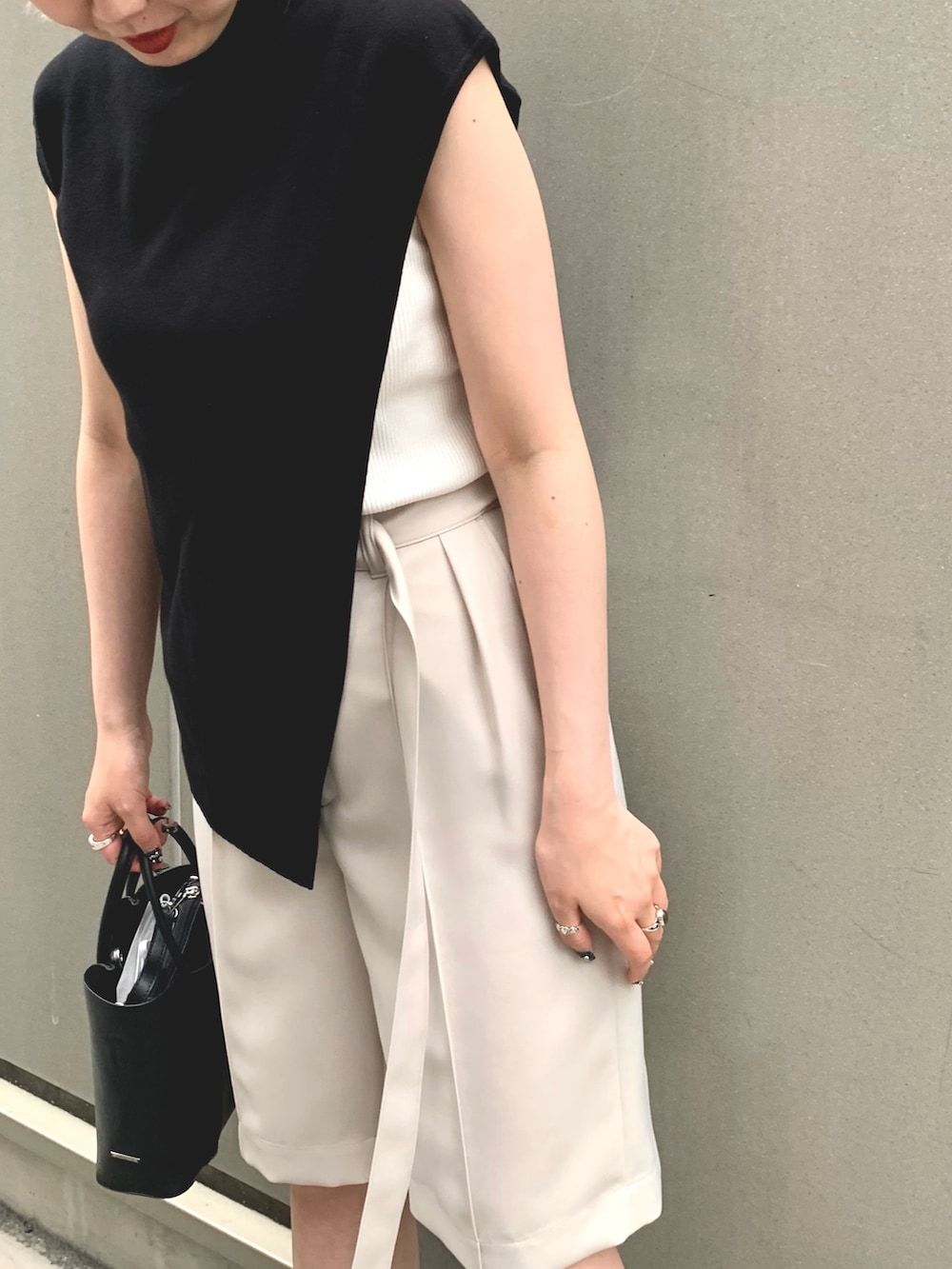 ブラック系のニット/セーター、ベージュ系のパンツ、ブラック系のハンドバッグを着用したレディースの夏コーディネートの2枚目の写真