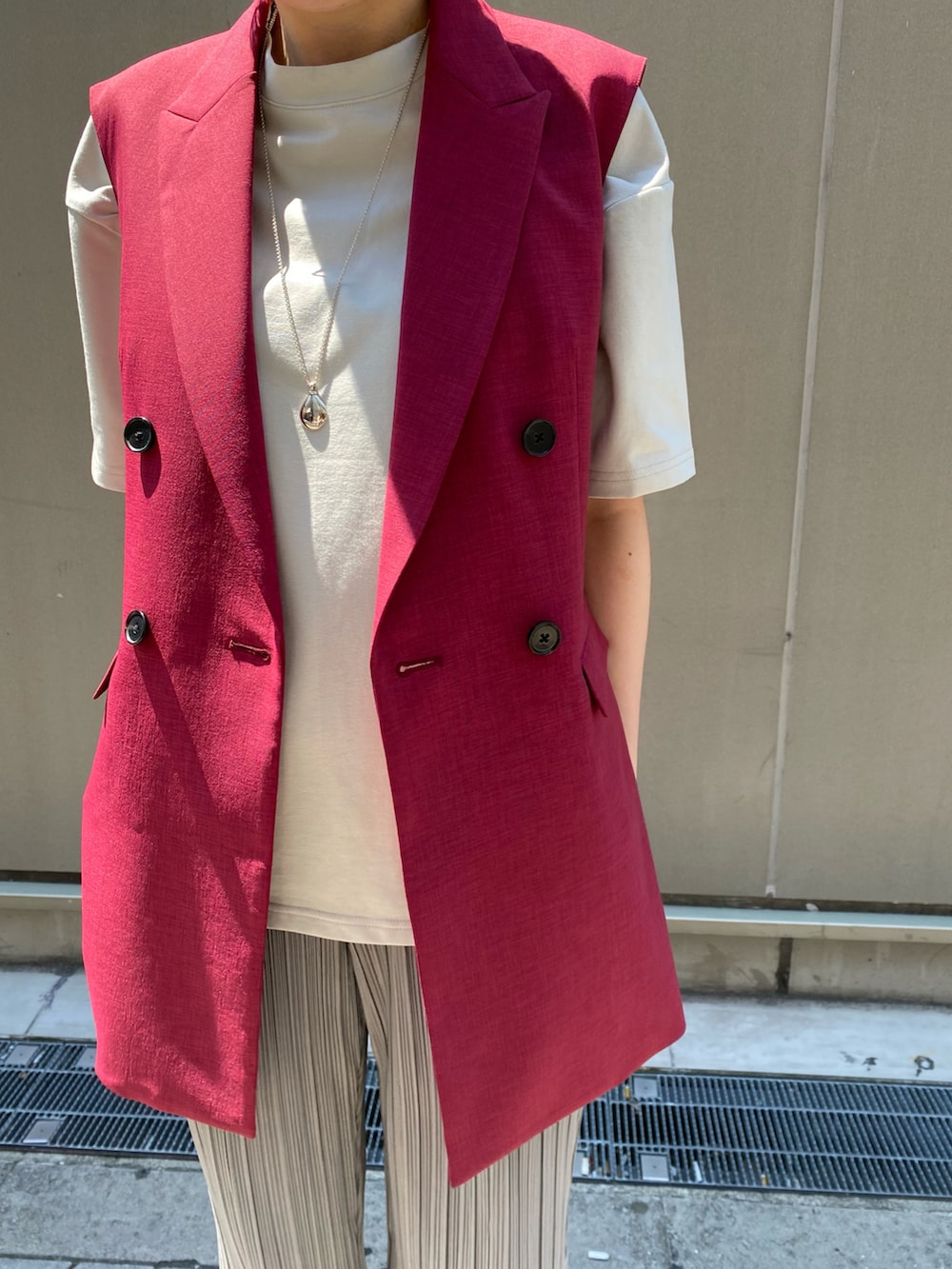 グレー系のその他パンツ、レッド系のベスト、シルバー系のアクセサリーを着用したレディースの春コーディネートの2枚目の写真