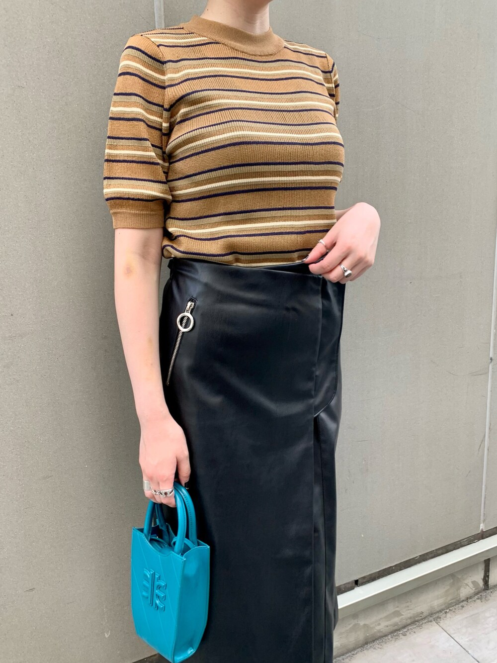 ブラウン系のトップス、ブルー系のバッグ、ブラック系のスカートを着用したレディースの夏コーディネートの2枚目の写真