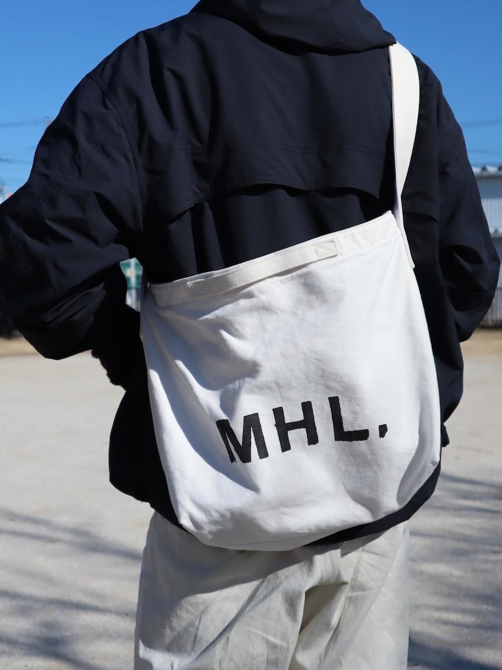 ブラック系のその他アウター、ベージュ系のチノパンツ、グレー系のスニーカーを着用したメンズの冬コーディネートの4枚目の写真