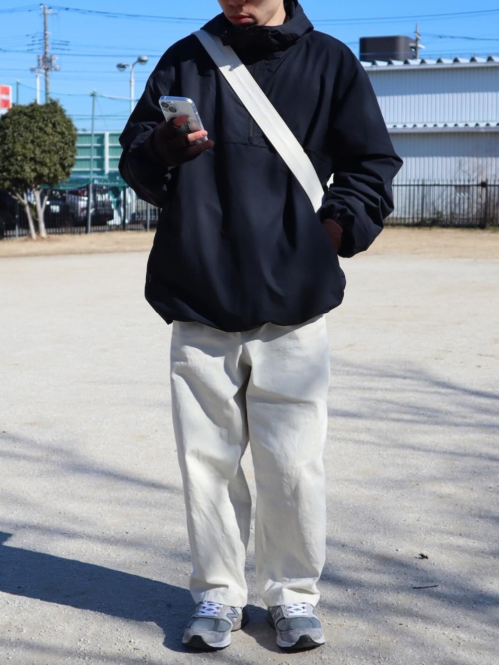 ブラック系のその他アウター、ベージュ系のチノパンツ、グレー系のスニーカーを着用したメンズの冬コーディネートの2枚目の写真